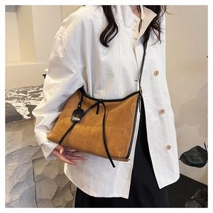 Detail of suede tote bag with black leather trim and drawstring on a model