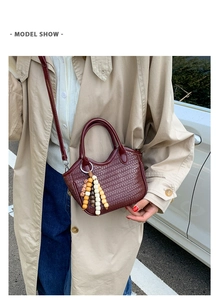Detail of burgundy woven bucket bag with beaded tassels and shoulder strap on model