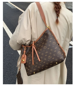 Braune Monogramm-Einkaufstasche mit Katzenprint in einer herbstlichen Straßenszene