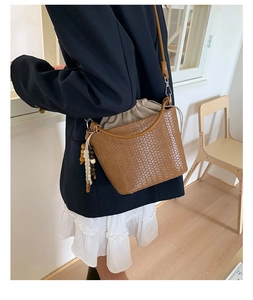 Detail einer braun gewebten Beuteltasche mit beigem Kordelzugfutter und Holzperlenquaste