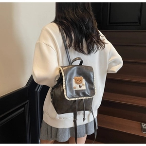 Detailed back view of a dark brown mini backpack with white lace trim and bear patch