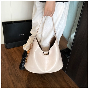Detail of beige hobo bag with glossy finish, chain strap and wooden bead charm