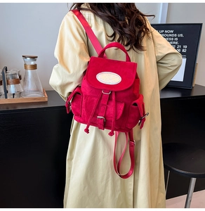 Détail d'un sac à dos en daim rouge vif avec rabat et plusieurs poches de rangement