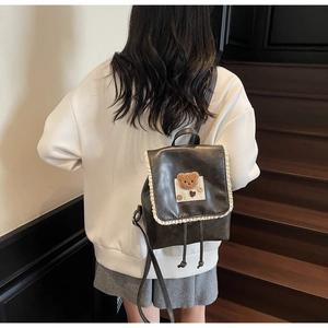 Detail of cute bear patch and lace trim on a dark brown aesthetic student backpack