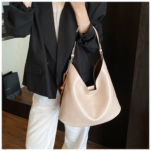 Beige crescent hobo bag with wood bead charm shown on a model in a black blazer
