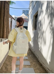 Outdoor shot of a cream white large capacity backpack worn by a female model
