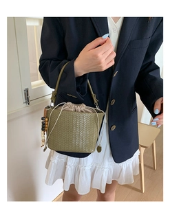 Detail of olive green woven bucket bag featuring drawstring liner and wooden bead charm