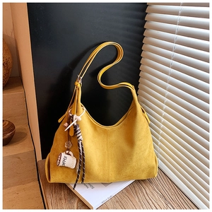 Détail d'un sac cabas en daim jaune vif avec un charm café et un ruban rayé déco