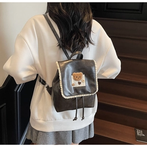 Close-up of dark grey lace teddy bear backpack with premium faux leather texture on stairs