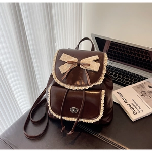 Detail of dark brown PU leather backpack with delicate cream lace trim and bow accents
