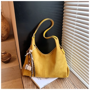 Détail du sac fourre-tout en daim jaune avec breloque café et nœud rayé