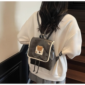Close-up of leather backpack with lace trim and plush bear patch on model's back