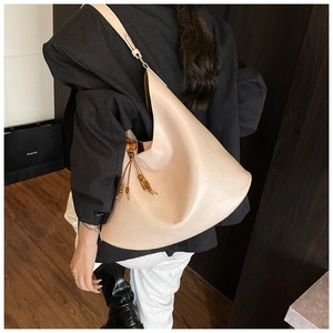 Beige crescent shoulder bag featuring fine PU leather texture and wooden bead tassel details