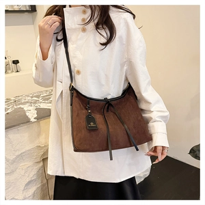Detail view of large dark brown suede tote bag featuring black leather trim and strap