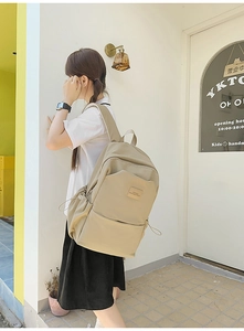 Side view of a khaki large-capacity nylon backpack worn by a model in an outdoor setting