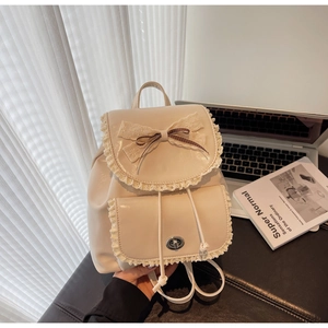 Détail du sac à dos vintage beige avec bordure en dentelle, nœuds et fermoir tournant en métal