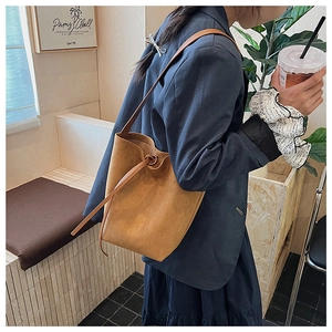 Detail view of brown suede bucket bag with decorative knot and slim shoulder strap