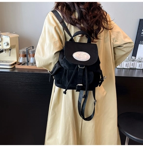 Détail du sac à dos noir avec emblème argenté et bretelles réglables sur modèle