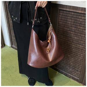 Close-up of deep brown retro leather tote bag featuring a wooden bead tassel charm