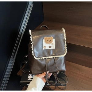 Close-up of brown PU leather backpack with delicate white lace trim and teddy bear embroidery