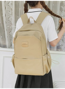 Rear view of khaki waterproof nylon backpack with drawstring side pockets and leather logo tag