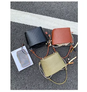 Overhead view of woven bucket bags in black, brown, and green with drawstring liners