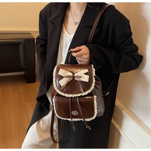 Close-up of vintage brown leather backpack with delicate lace trim and ribbon bow