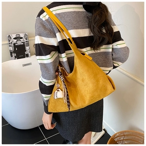 Détail d'un grand sac cabas jaune en daim avec pompon rayé et breloque tasse à café