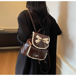 Detail of vintage brown PU backpack featuring lace trim and large decorative bow design