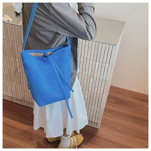 Macro detail of high-saturation blue suede bucket bag with stylish drawstring tie
