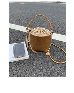 Detailed close-up of a brown woven bucket bag with beige drawstring inner lining