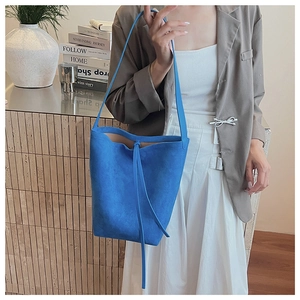 Close-up of royal blue suede bucket bag with long strap and minimalist design