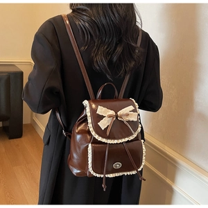 Detail of vintage brown PU leather backpack with lace trim and bow knot decoration