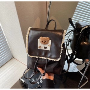 Detail of vintage brown PU leather backpack with lace trim and 3D plush bear motif