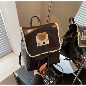 Close-up of brown lace-trimmed backpack with teddy bear patch and drawstring closure