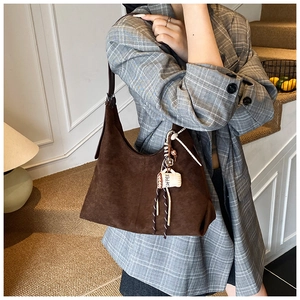 Gros plan d'un sac hobo en daim marron foncé avec charm tasse à café et bandoulière élégante