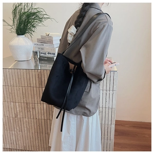 Close-up of minimalist black suede tote bag showing soft texture and shoulder strap