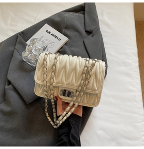 Detail der cremefarbenen Stepptasche mit Silberkette und glitzerndem Verschluss