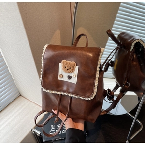 Detail of vintage brown PU leather backpack with lace trim and plush bear embroidery