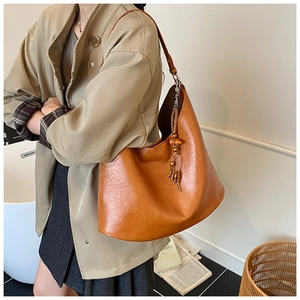 Macro detail of caramel lychee grain leather hobo bag with vintage tassel ornament