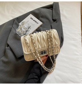 Detailaufnahme der cremefarbenen Stepptasche mit Kettenriemen auf einem Blazer
