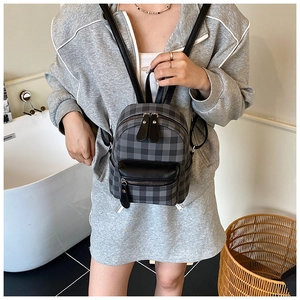 Mini-Rucksack mit grauem Karomuster und schwarzem Leder, getragen zum Streetwear-Outfit