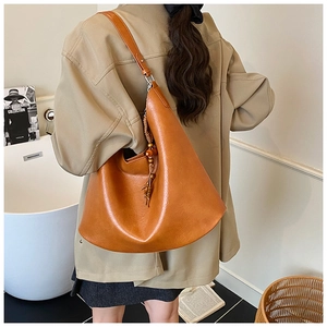 Detail of caramel leather hobo bag with long shoulder strap and wooden bead tassel