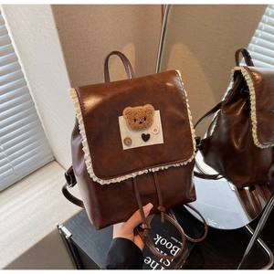 Detail of vintage coffee PU leather backpack with lace trim and plush bear badge