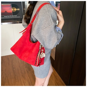 Détail du sac hobo en daim rouge avec pendentif tasse à café et pampilles élégantes