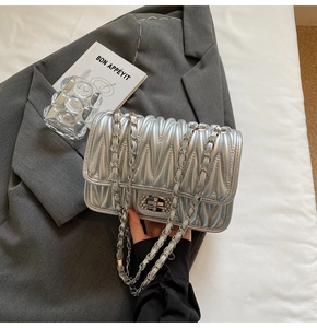 Detail einer silbernen Stepptasche mit glitzernder Strassschnalle und Metallkettenriemen