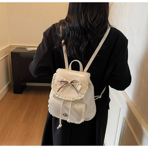 Detail of cream mini lace backpack with brown ribbons shown on model back