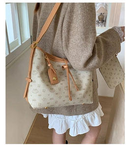Detail der beigen Beuteltasche mit Lazy-Breeze-Muster und passendem Etui am Modell