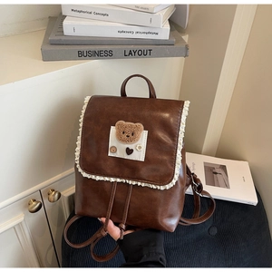 Close-up of brown PU leather backpack with delicate white lace trim and teddy bear detail