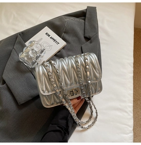 Detail einer silbernen Stepptasche mit Strass-Drehverschluss und Metallkettenriemen